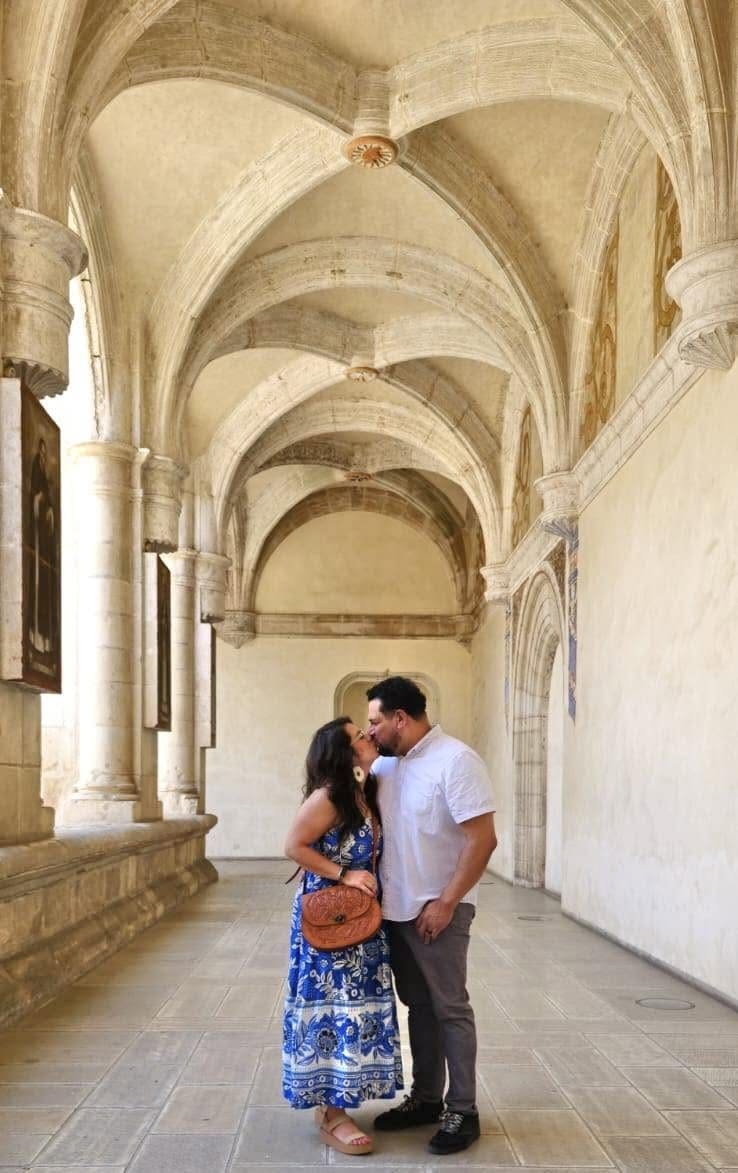 Couple kissing in a sunlit cloister hallway with stone arches in Oaxaca, Mexico