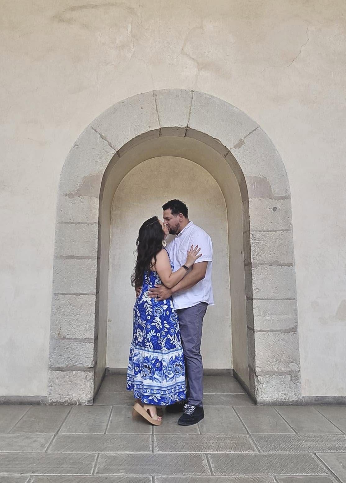 Newlywed couple kissing beneath a stone archway in Oaxaca City, Mexico
