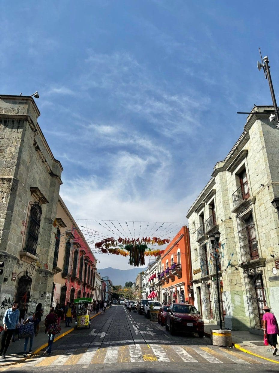 Colorful colonial buildings and papel picado banners lining a sunny street in Oaxaca City, Mexico
