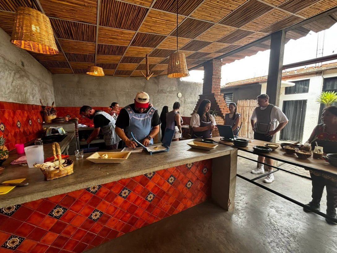 Group cooking class in an outdoor kitchen with red tilework in Oaxaca