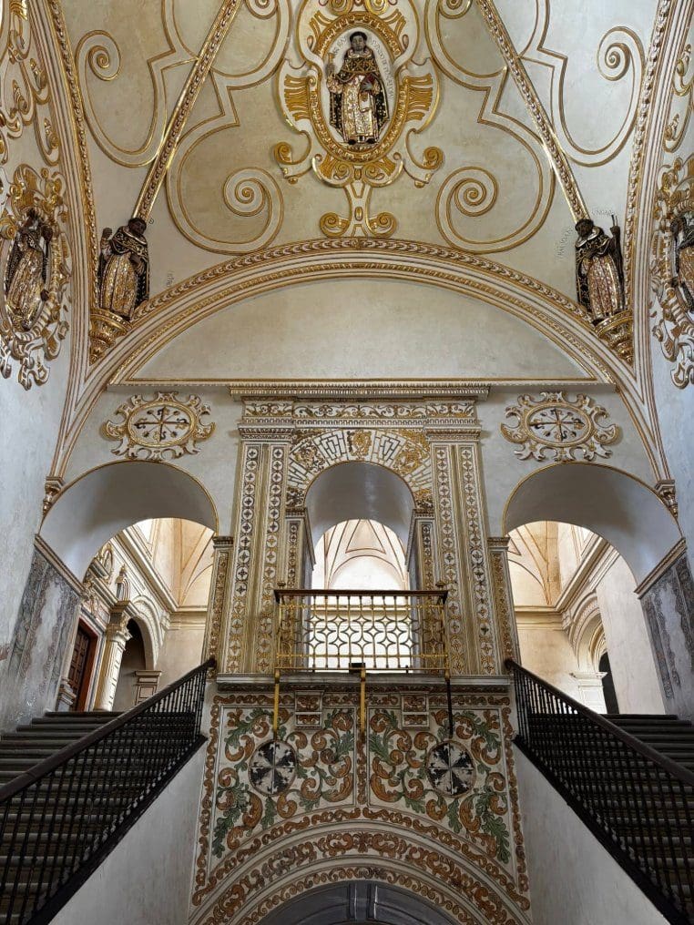 Ornate gold and white vaulted ceiling and grand staircase inside a historic church in Oaxaca City