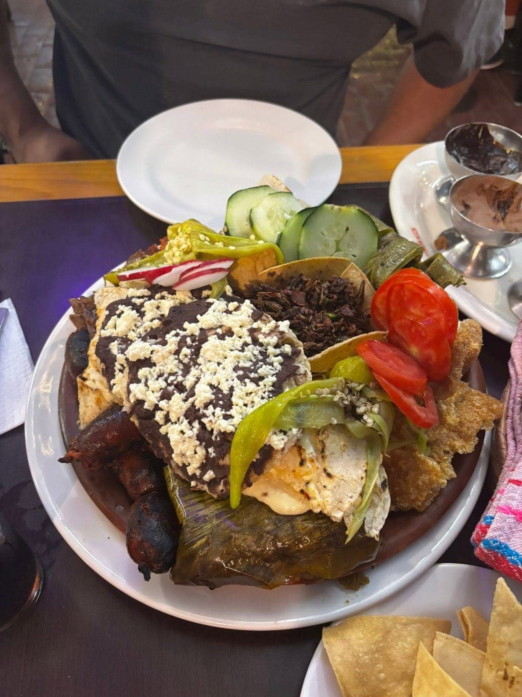 Colorful Oaxacan botana platter with tlayuda, quesillo, chapulines, and fresh vegetables
